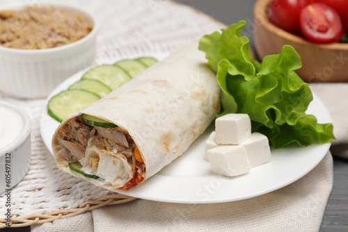Delicious tortilla wrap with tuna on grey wooden table