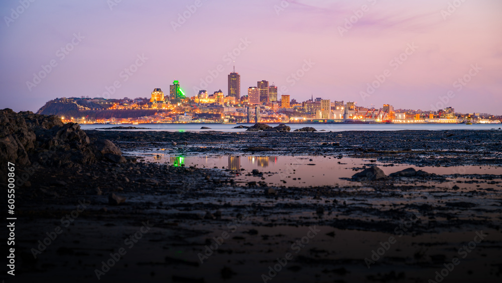 Quebec city's silhouette at dusk, under vibrant colored sky, seen from Orleans island, Canada