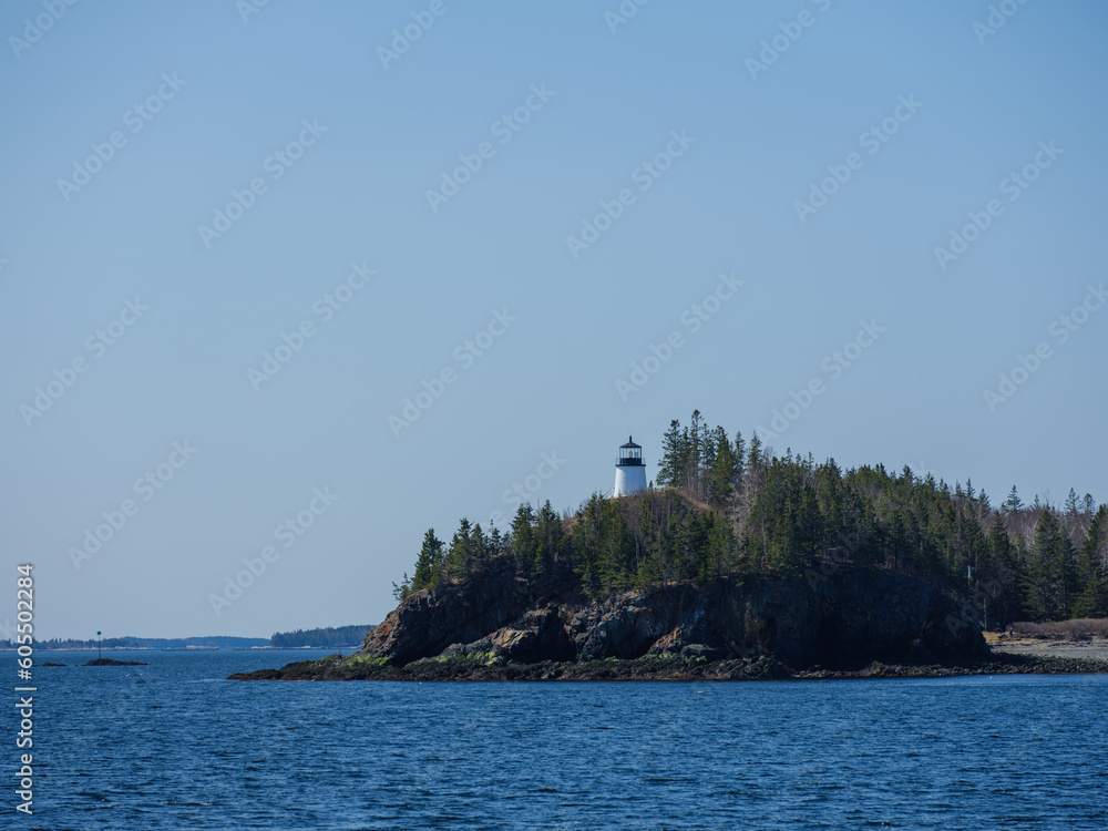 The Owls Head Lighthouse sit atop the cliffs as seen from the water and the Vinalhaven Ferry