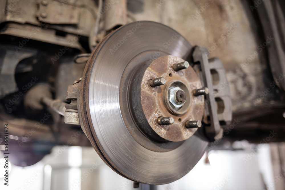 Disc brake of the vehicle for repair, in process of new tire replacement. Car brake repairing in garage.Suspension of car for maintenance brakes and shock absorber systems. Replacement of brake pads. Disc brake of the vehicle for repair, in process of new tire replacement. Car brake repairing in garage.Suspension of car for maintenance brakes and shock absorber systems. Replacement of brake pads.