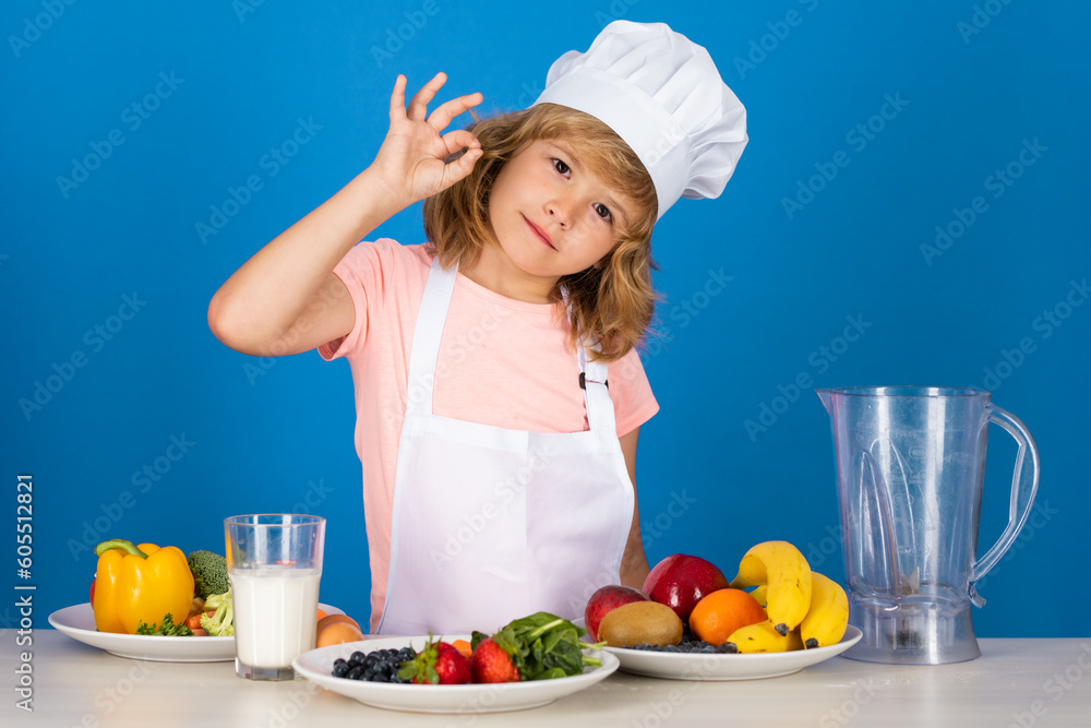 Fruits and vegetables for kids. Kid boy in chef hat and apron cooking preparing meal. Little cook with vegetables at kitchen. Natural kids food. Fruits and vegetables for kids. Kid boy in chef hat and apron cooking preparing meal. Little cook with vegetables at kitchen. Natural kids food.