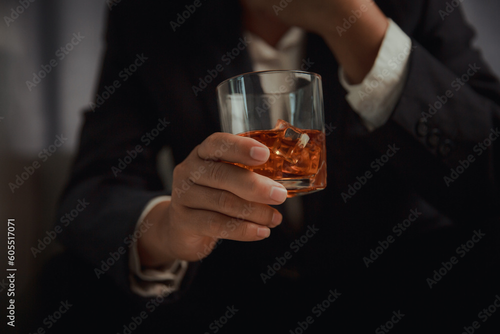 Businessman in black suit holding glass of whiskey Celebrate company success close-up