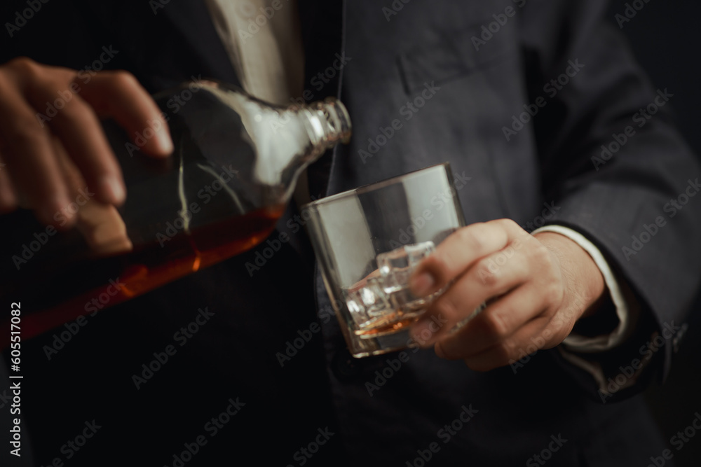 Businessman in black suit holding glass of whiskey Celebrate company success close-up