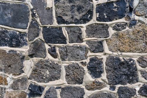 A rock wall texture with various sized stones cemented into a wall feature photo