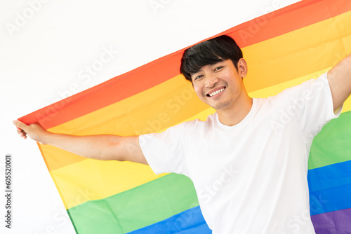 Cheerful young man wrapped in rainbow flag enjoying isolated on white background. Homosexual lgbtiq concept  rainbow flag  celebrating parade. Copy space.