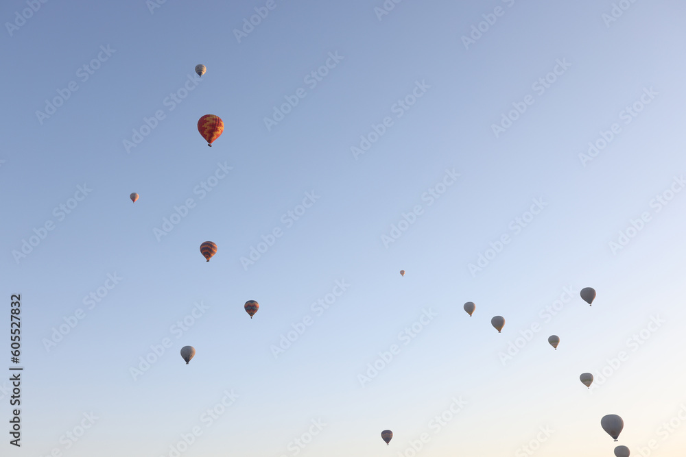 Multi-colored balloons floating up in air against blue sky