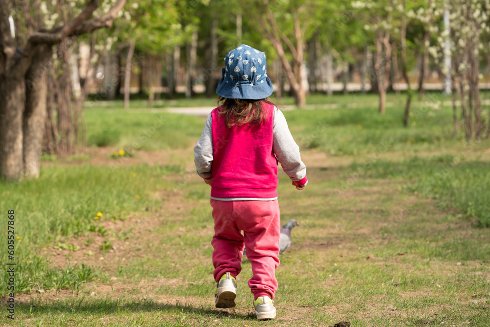 A two-year-old girl runs after pigeons in a city park. A two-year-old girl runs after pigeons in a city park.
