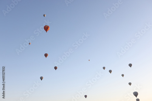 Multi-colored balloons floating up in air against blue sky