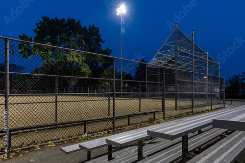 Fotografía vue sur un terrain de baseball clôturé avec du sable au milieu tard le soir avec