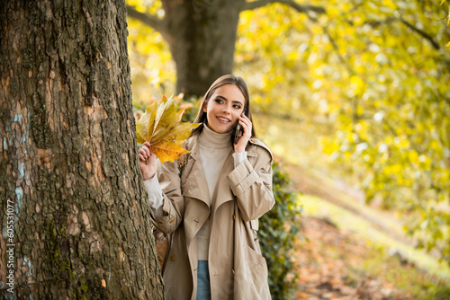 Young woman in autumn park. Warm sunny weather. Fall concept. Hello autumn. Happy woman with autumn yellow leaves outside. Beautiful autumn fall time in nature.