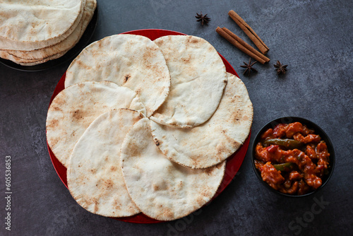 Freshly baked arabic or Pakistani flat bread Kuboos or roti on a black background. Kuboos or khubz fresh pita bread with chilly chicken curry photo