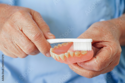 Asian senior woman patient brush teeth denture with toothbrush for chew food.