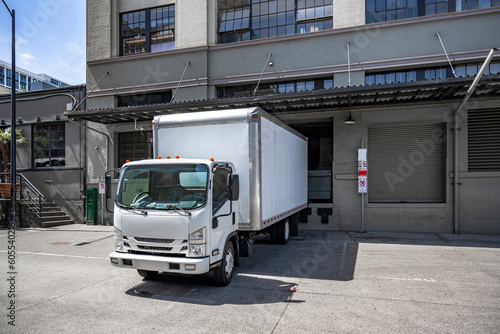 Fototapeta Naklejka Na Ścianę i Meble -  Small cabover rig semi truck with box trailer loading cargo standing in the warehouse dock on the city street
