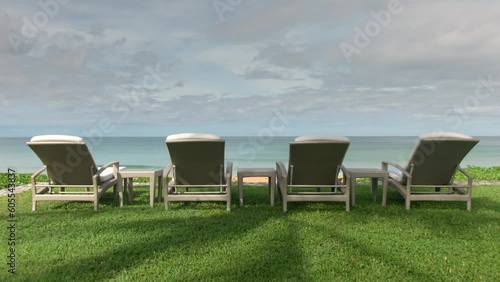 Wide shot of grass field near the beach with four sunbeds under the summer sun, waiting for guests, hollydays concept photo