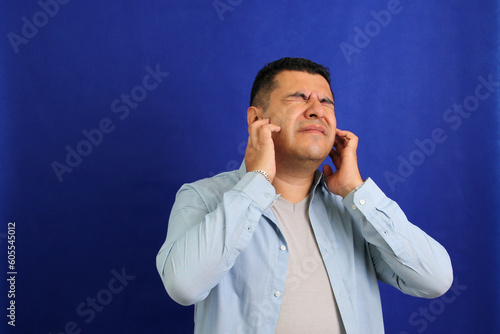 Adult 40-year-old brown Latino man suffers from pain in the ears due to otitis, hypocausia or vertigo