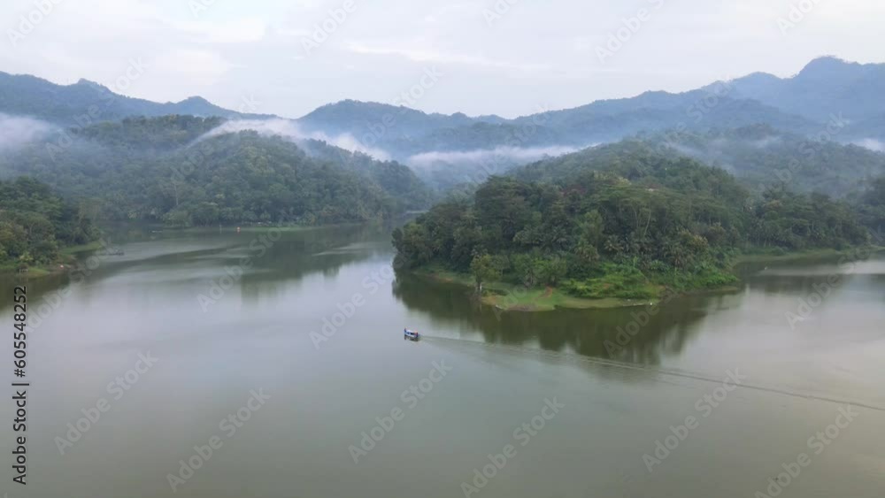 Drone shot of boat on idyllic lake surrounded by mountain in the misty morning - Indonesia,Asia Drone shot of boat on idyllic lake surrounded by mountain in the misty morning - Indonesia,Asia