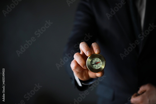 man in suit holding golden compass on gray background