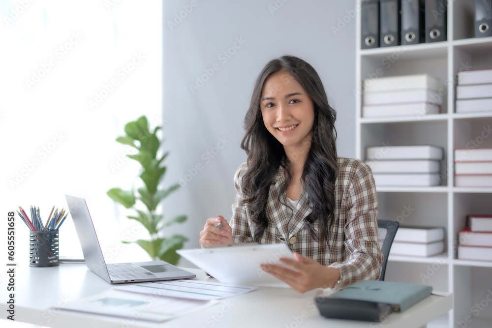 Beautiful young female manager or company worker holding accounting documents, checking financial data or marketing reports working in office with laptop. Accountant consults on some document. Beautiful young female manager or company worker holding accounting documents, checking financial data or marketing reports working in office with laptop. Accountant consults on some document.