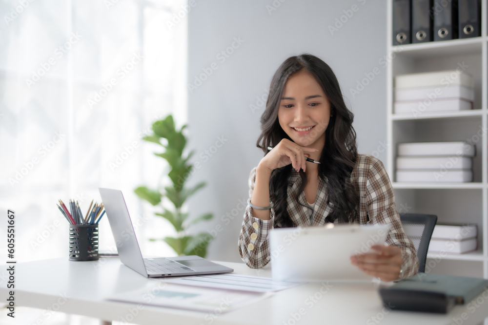 Beautiful young female manager or company worker holding accounting documents, checking financial data or marketing reports working in office with laptop. Accountant consults on some document. Beautiful young female manager or company worker holding accounting documents, checking financial data or marketing reports working in office with laptop. Accountant consults on some document.