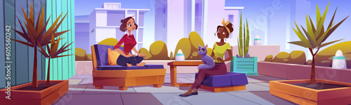 Two women talking on terrace in big city. Vector cartoon illustration of female friends sitting on chairs with cat on lap, urban apartment balcony with cozy furniture and lamps. Cityscape background