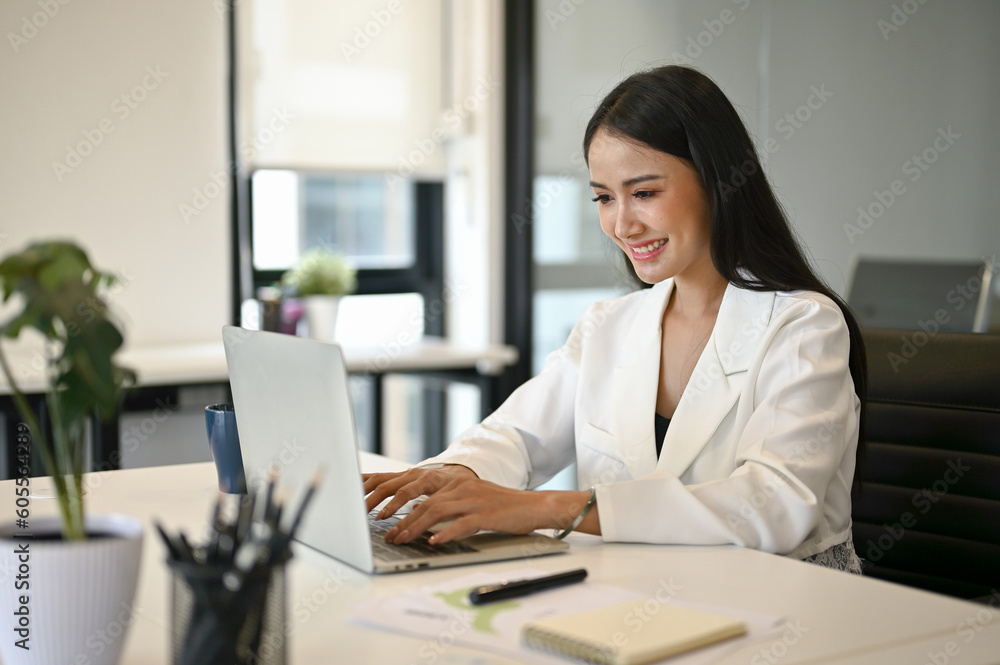 Successful Asian businesswoman typing on laptop keyboard, using her laptop Successful Asian businesswoman typing on laptop keyboard, using her laptop