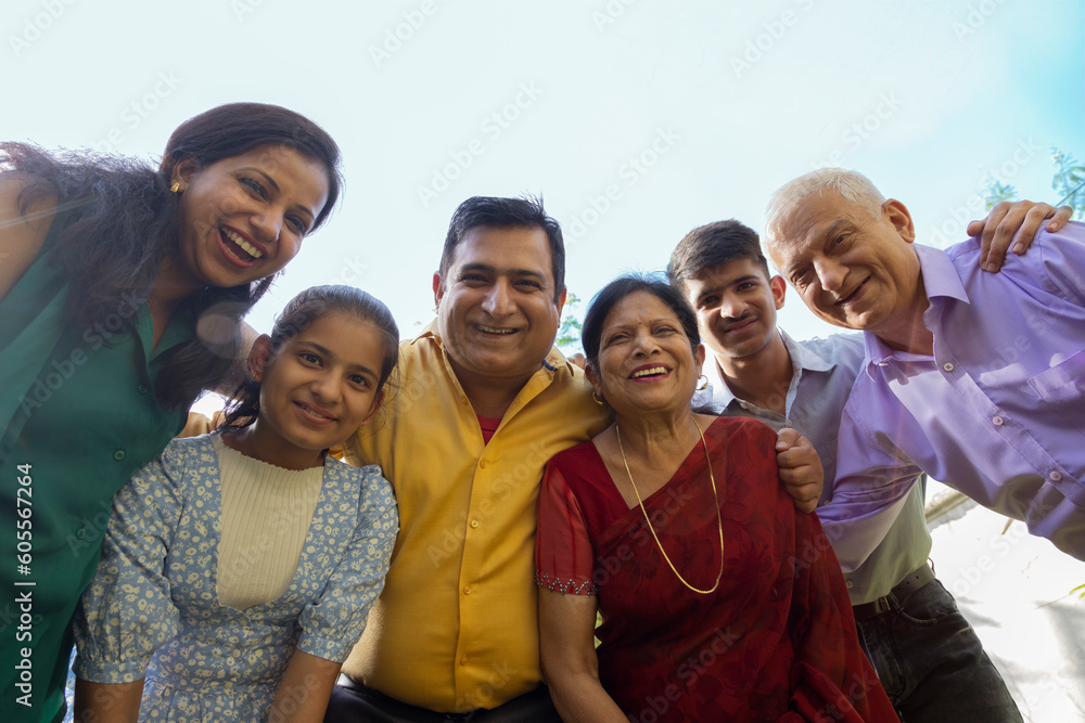 Low angle view of happy multi generation Indian family standing together in backyard