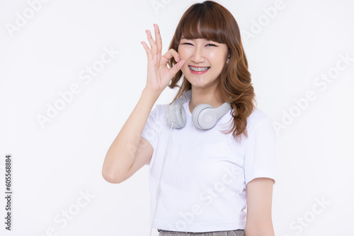 Close up young Asian girl smile with braces making OK hand signal isolated on white background. Dental care concept.