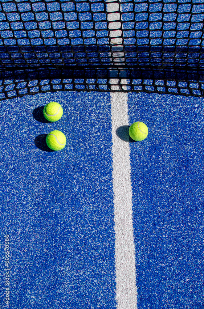 three balls near the net in a blue paddle tennis court, racket sports concept