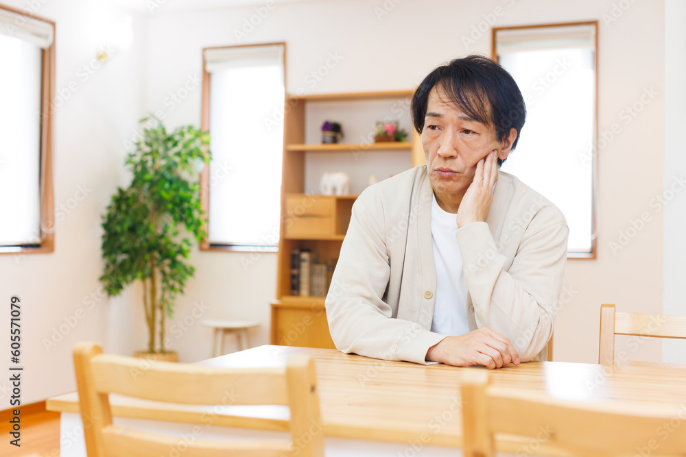 ダイニングテーブルに座って考えている成熟した日本人
