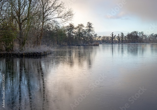 Winter landscape with a frozen river and trees in the foreground on a cloudy day