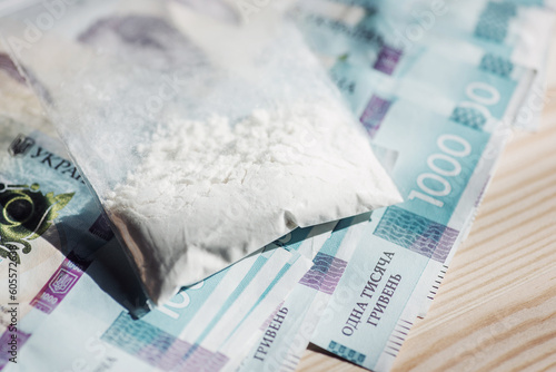 Plastic bag full of cocaine or other drugs on ukrainian money banknotes. Concept of trade of drugs, toned photo