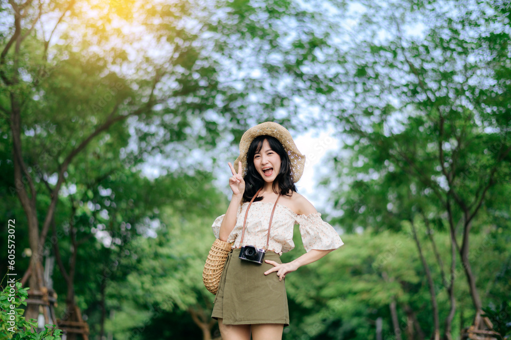 Portrait of asian young woman traveler with weaving hat and basket and a camera on green public park nature background. Journey trip lifestyle, world travel explorer or Asia summer tourism concept. Portrait of asian young woman traveler with weaving hat and basket and a camera on green public park nature background. Journey trip lifestyle, world travel explorer or Asia summer tourism concept.