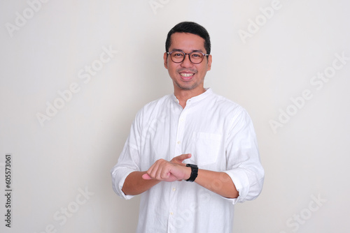 Adult Asian man smiling happy while pointing to his watch photo