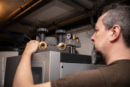 Foto male plumber with pipe wrench installs a new pellet heater in the basement