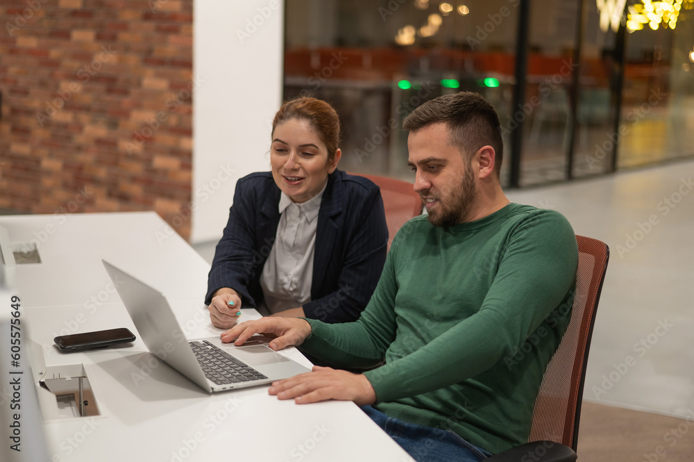 Caucasian bearded man and red-haired woman work in a modern coworking space. Colleagues discuss work. Caucasian bearded man and red-haired woman work in a modern coworking space. Colleagues discuss work.