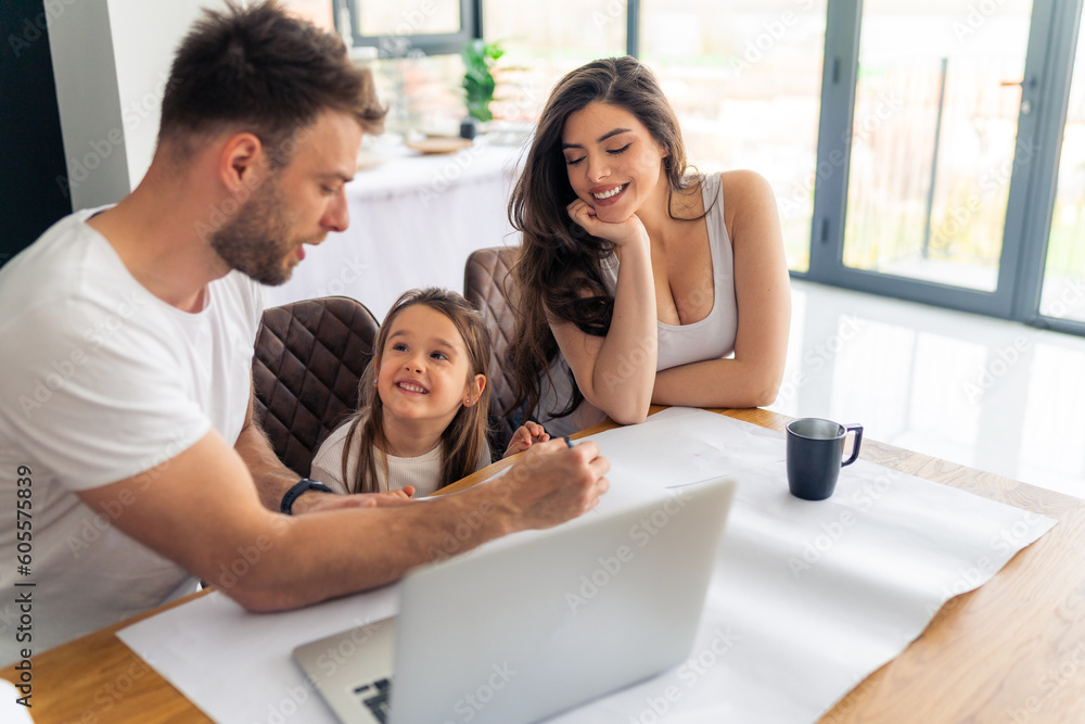 Parents sitting with their daughter at the desk and making plans for her Parents sitting with their daughter at the desk and making plans for her