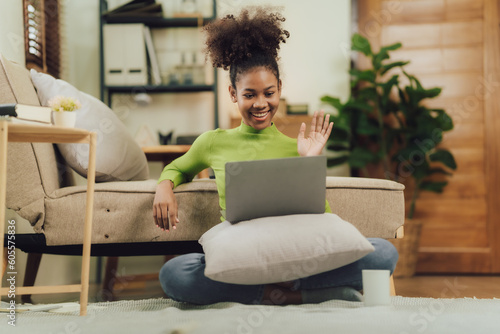 Focused young African female college student working on a laptop on living room.