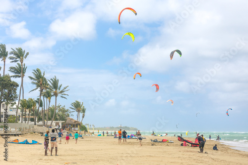 Crowd of active sporty people enjoying kitesurfing holidays and activities on perfect sunny day on Cabarete tropical sandy beach in Dominican Republic