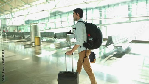 Male traveler walking in an empty airport with backpack and carry-on