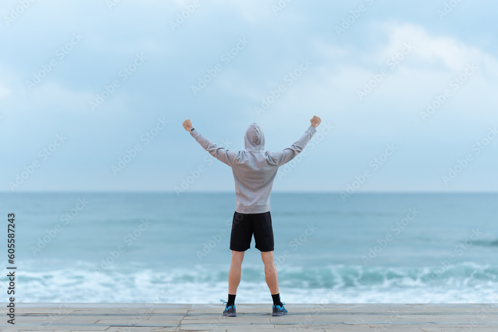 Full body of sportsman looking seascape with outstretched arms Full body of sportsman looking seascape with outstretched arms