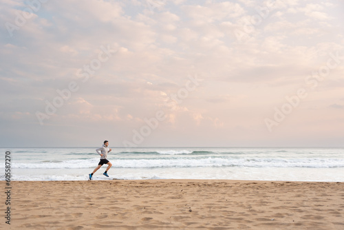 Sportsman running at the beach at sunrise