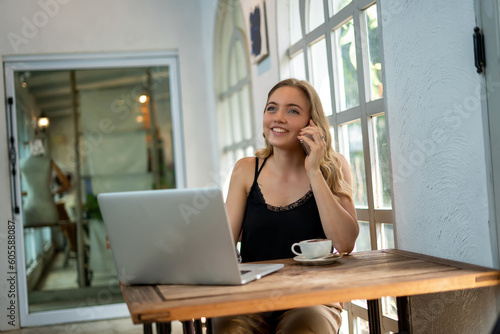 A young beautiful designer woman working outside the office using laptop searching for online concepts in cafe.