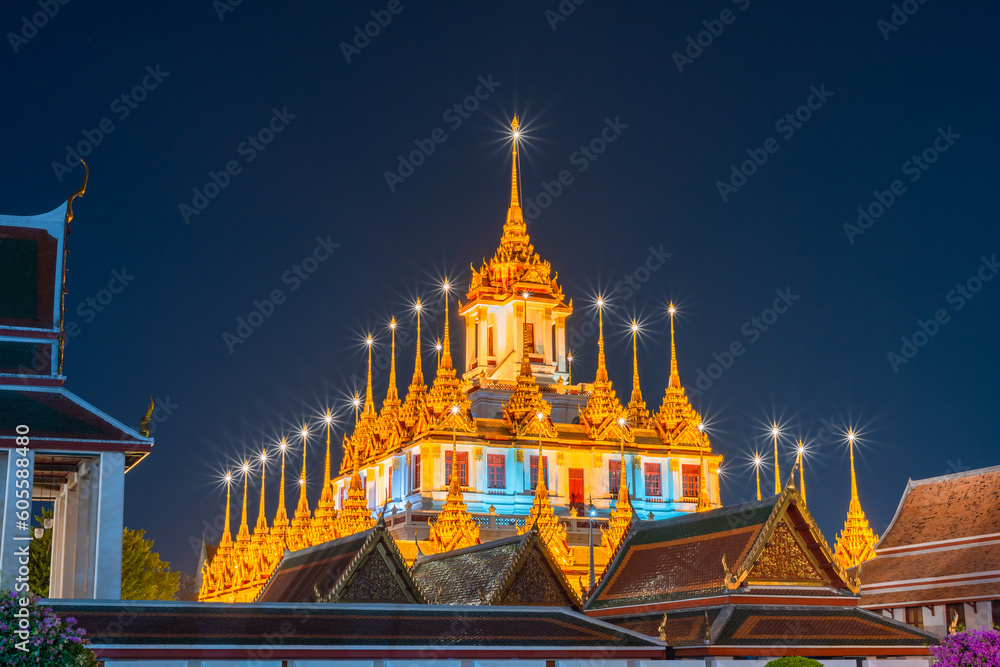 Naklejka premium The Loha Prasat, Wat Ratchanatdaram Worawihan at night that is turning on a beautiful yellow light which is one of the famous temples in Bangkok