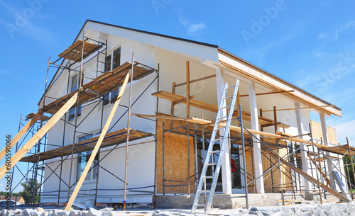 Painting house wall facade during exterior renovations. Painting facade house walls after renovation and remodel with stucco, plastering, insulation.