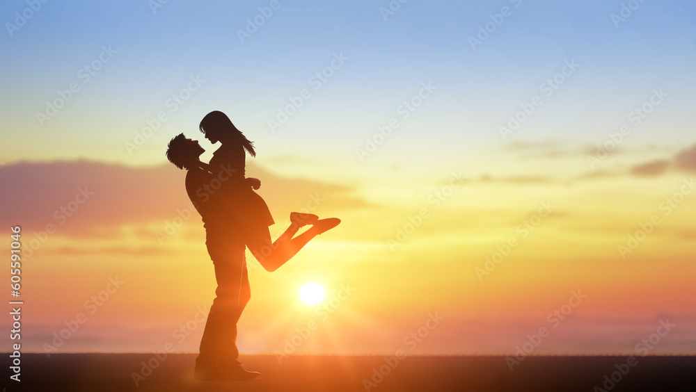 Couple kissing with beautiful sunset in background, man lifting woman. Couple in love silhouette during sunset, backlit. copy space