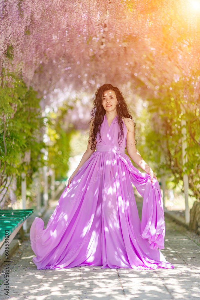 Woman wisteria lilac dress. Thoughtful happy mature woman in purple dress surrounded by chinese wisteria