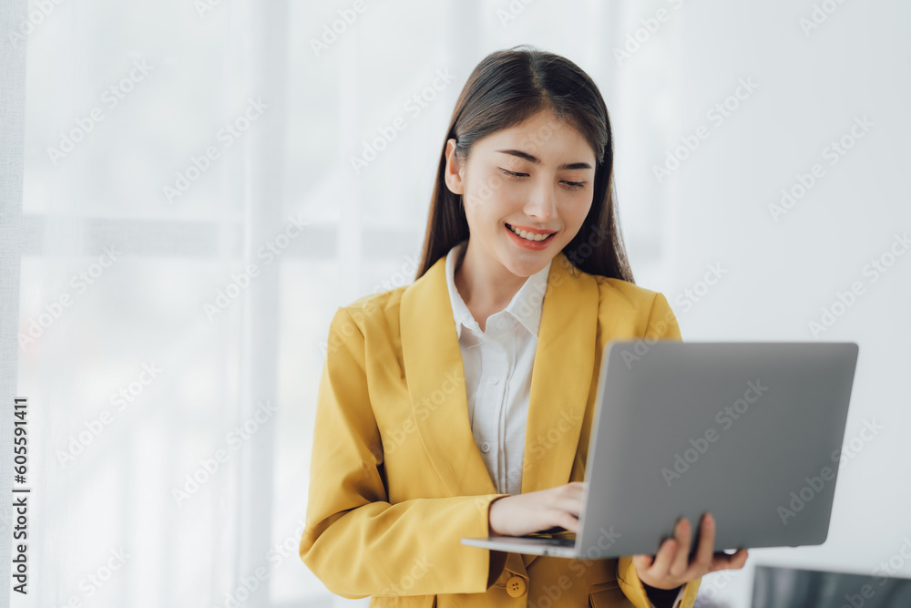Young female Asian businesswoman having a phone call with her coworker in the office room. Young female Asian businesswoman having a phone call with her coworker in the office room.