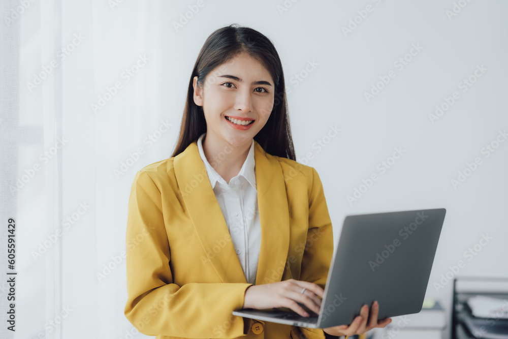 Young female Asian businesswoman having a phone call with her coworker in the office room. Young female Asian businesswoman having a phone call with her coworker in the office room.