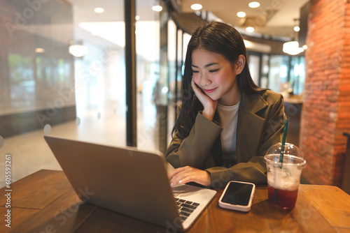 Fotografia Happy business freelance asian woman using laptop computer at cafe urban lifesty