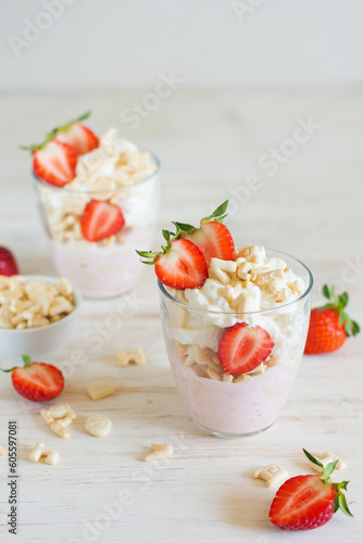 Desserts of cookies and whipped cream with strawberries in glasses, background in blur.